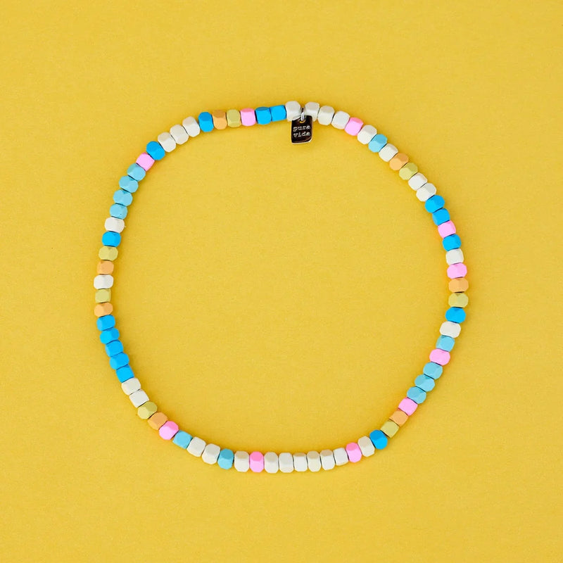 Multi colored hematite anklet is laying on a flat surface. Here you can tell it is a stretch, pull over type style. 