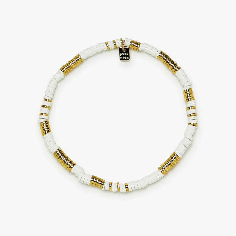 Shows anklet with white and gold flat beads. Has a small rectangular charm with "pura vida" on it.