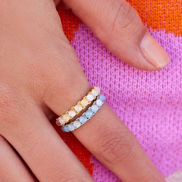 Shows model wearing both the gold and silver color ways of this ring. Features stones along the band in an ombre fashion.