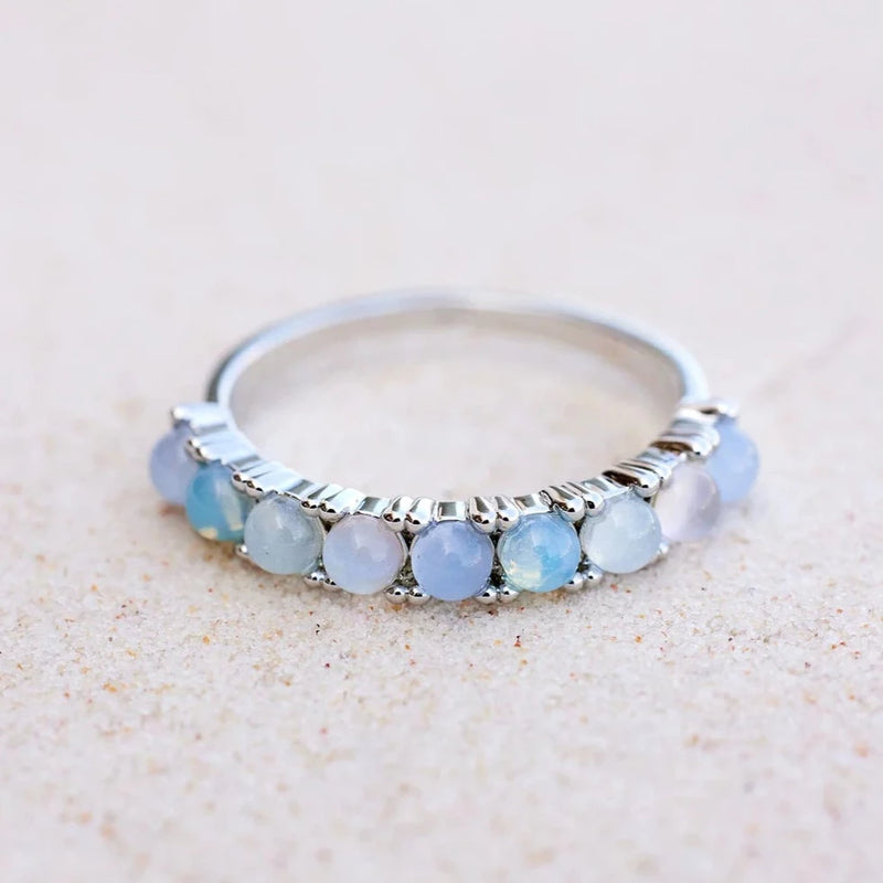 Front of silver ring where 9 opal and glass stones are affixed on the front of the band in an ombre fashion.