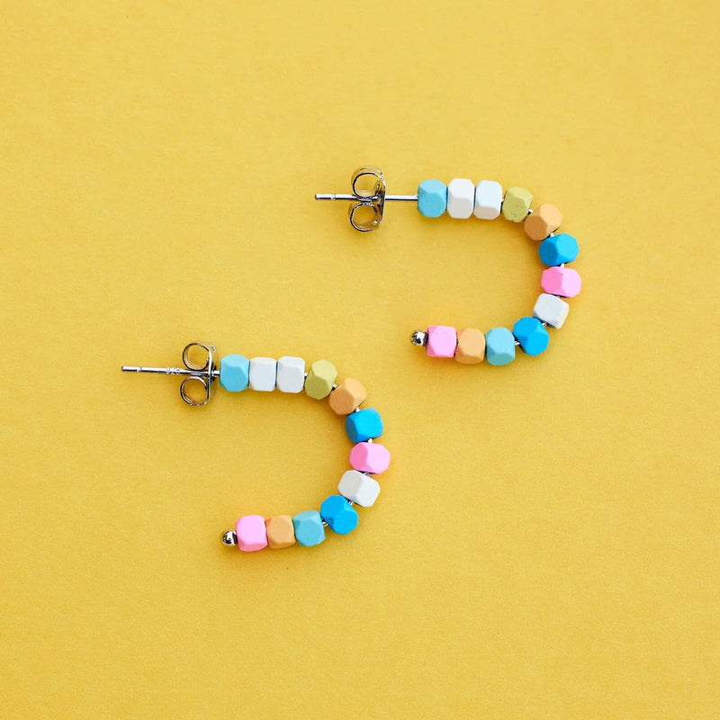 Shows the earrings laying on their side on a flat surface. Here you can see the half hoop  stlye, the silver post and the multi colored hematite beads.