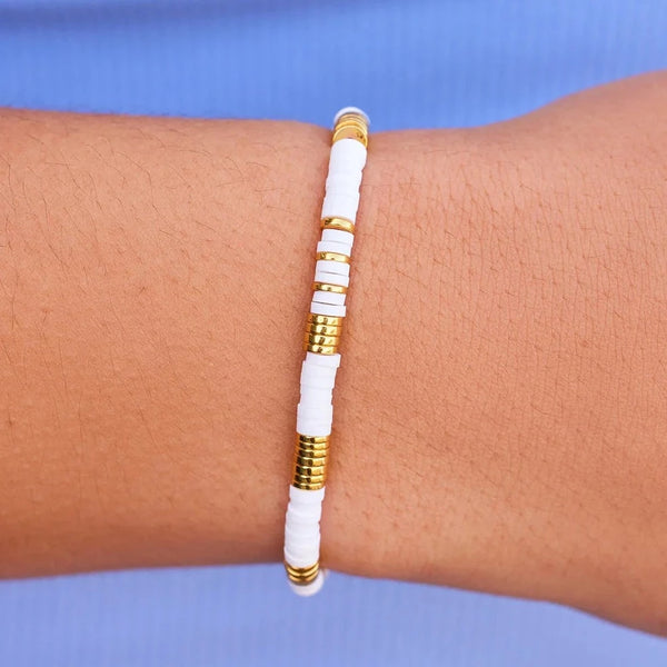 Another view of bracelet on models wrist. Shows a close up of the flat white and gold beads.