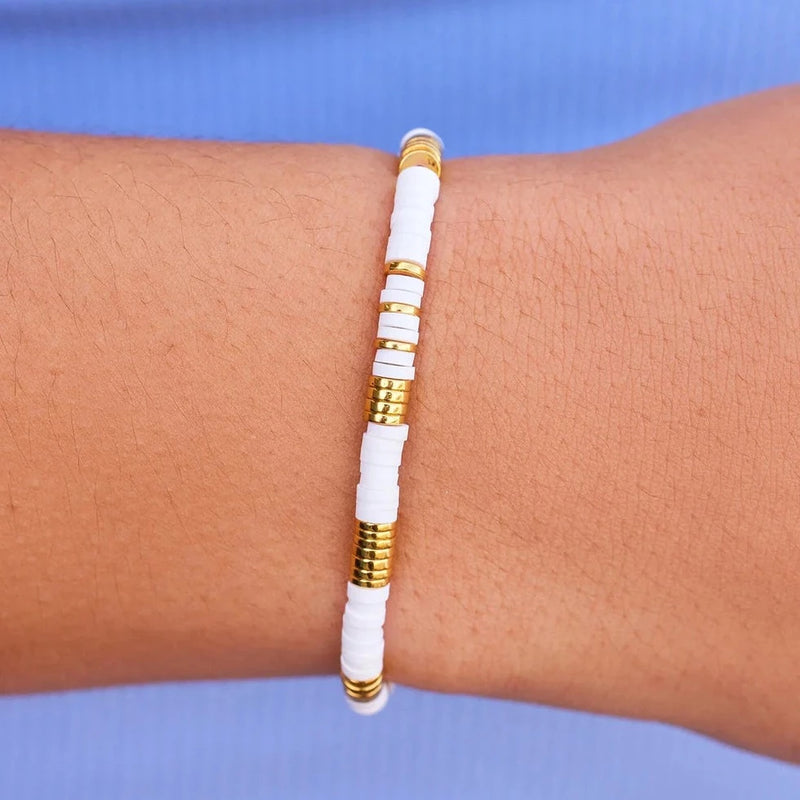Another view of bracelet on models wrist. Shows a close up of the flat white and gold beads.