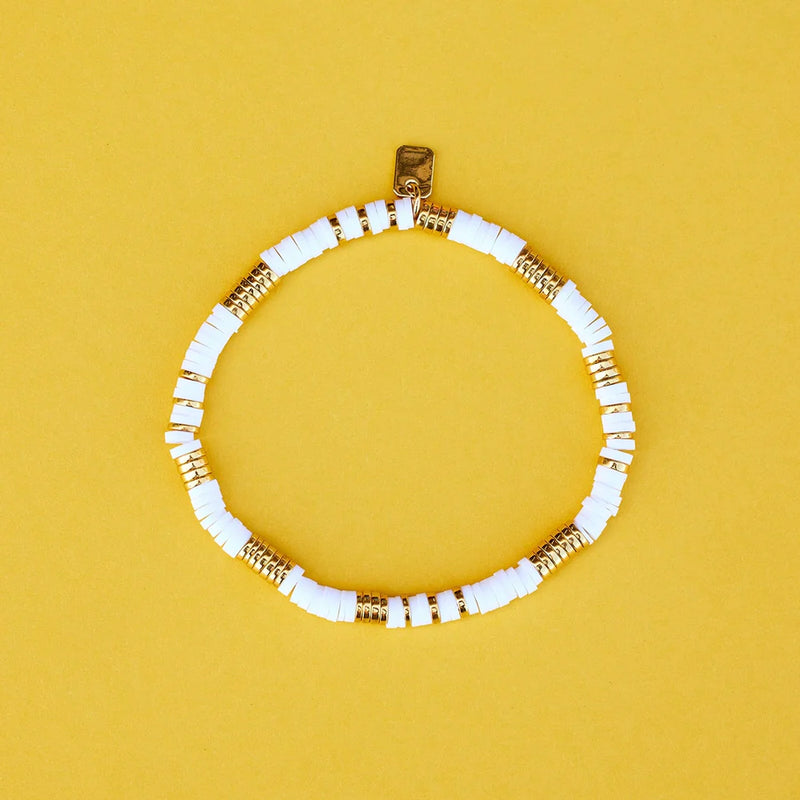 View of the bracelet laying on a flat surface.  Stretch, pull on style. Shows flat white and gold beads.