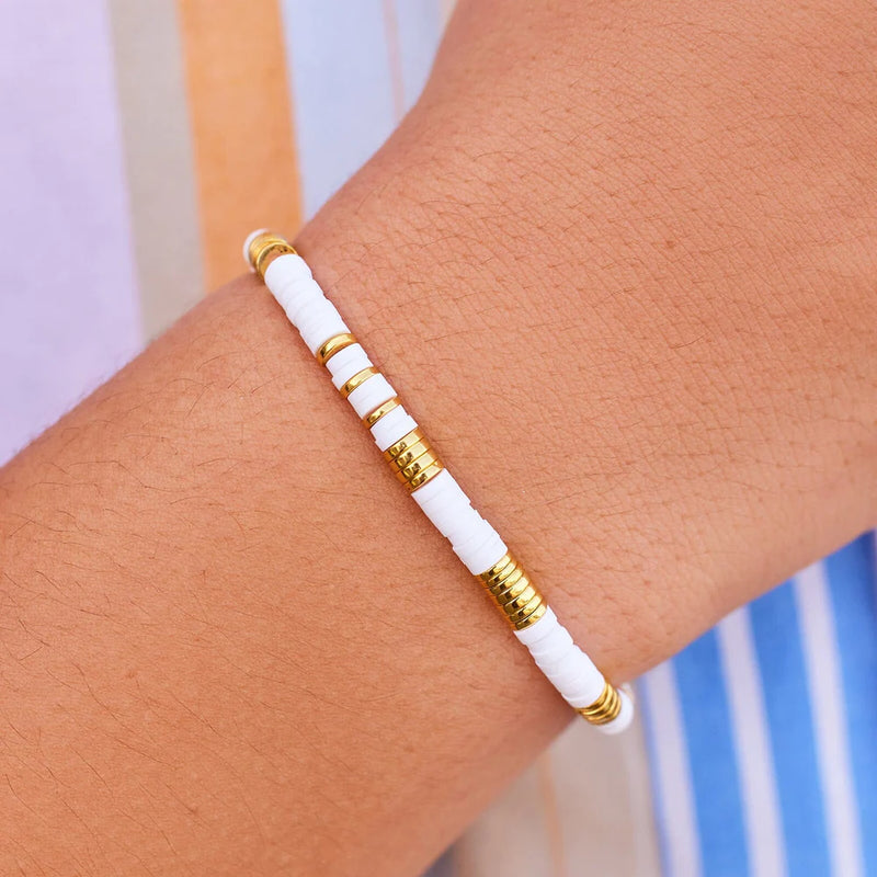 Shows bracelet on models wrist. Features white and gold flat beads