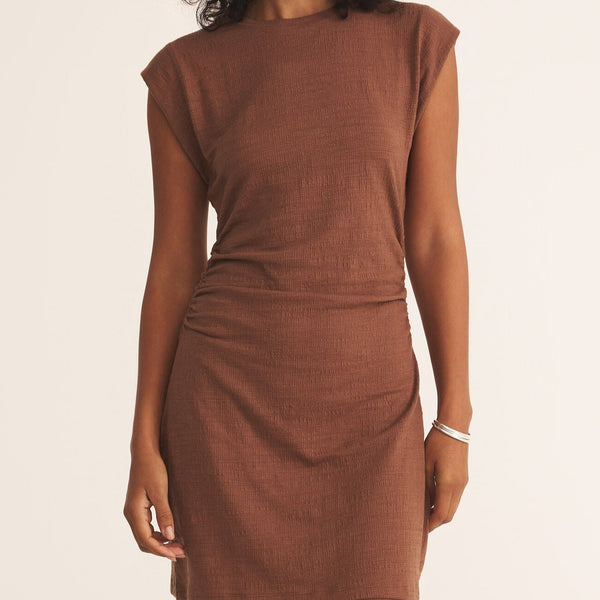 front view of the model wearing the camino textured mini dress. shows the crew neckline. also shows the cap sleeves, the synched waist and the fitted look. 
