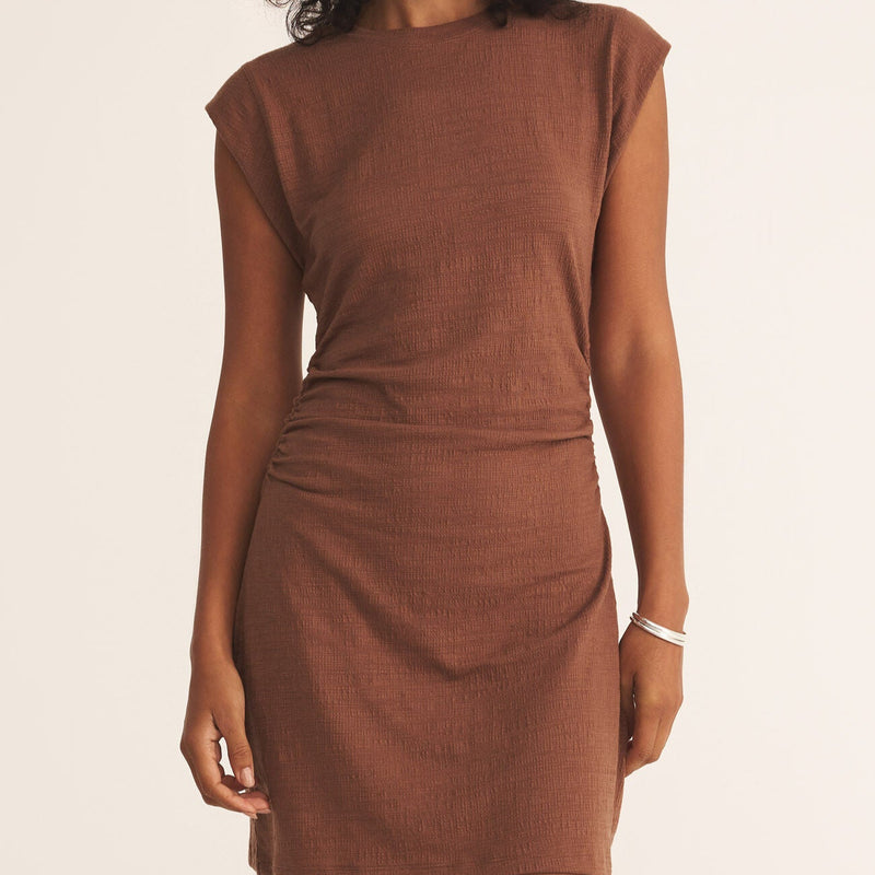 front view of the model wearing the camino textured mini dress. shows the crew neckline. also shows the cap sleeves, the synched waist and the fitted look. 