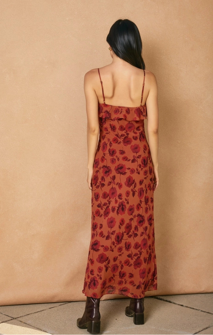 model wearing red floral dress with spaghetti straps and boots on a tan background. 