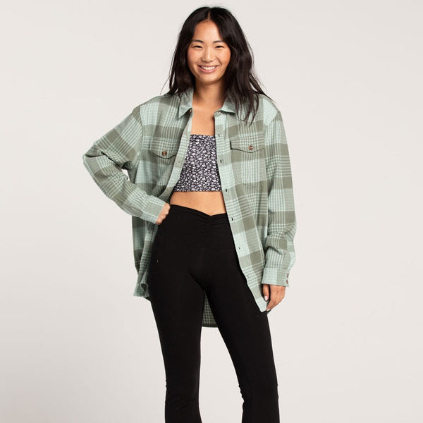 shows front view of model in flannel top. shows oversized fit, two front pouch pockets with flap closures and buttons down the front.