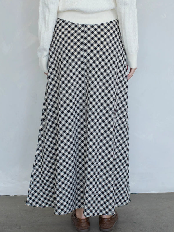 Person wearing a black and white checkered skirt against a plain background