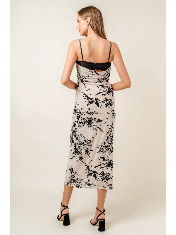 back view of the model wearing the vanessa velvet floral mesh midi dress. shows the lace bra detail. also shows the adjustable spaghetti straps, the midi length, the back cowl neckline and the black floral design throughout. 