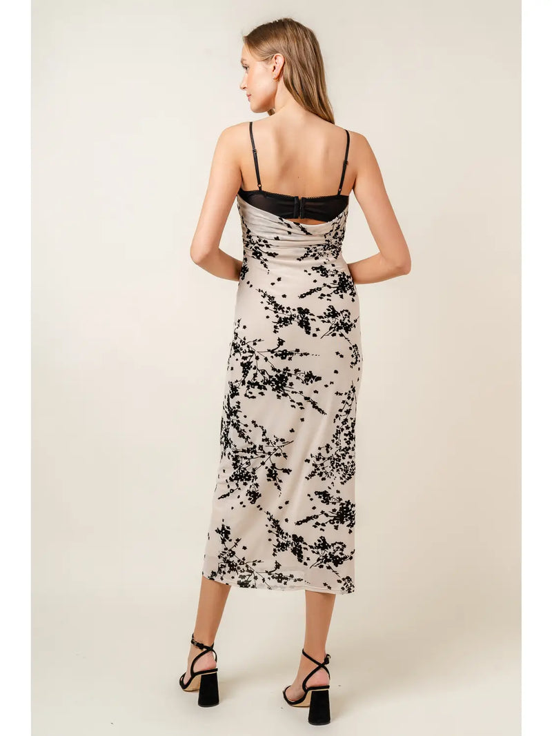 back view of the model wearing the vanessa velvet floral mesh midi dress. shows the lace bra detail. also shows the adjustable spaghetti straps, the midi length, the back cowl neckline and the black floral design throughout. 