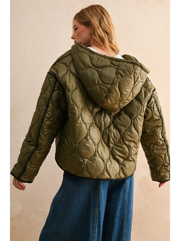 model wearing the olive quilted jackets with blue jeans against a cream back ground.
