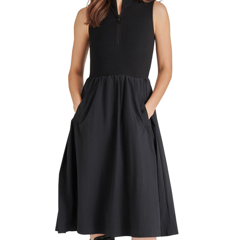 front view of model in dress. shows the knit bodice with fixed collar, half zip, and lightweight nylon skirt with pockets.