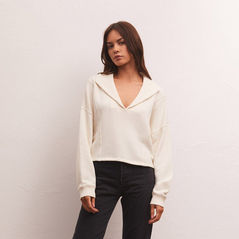 shows front view of model in sweatshirt. shows the slplit neck, long sleeves with dropped shoulders and exposed seams on the front.