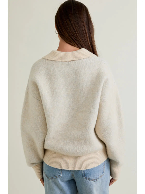 Person wearing a beige sweater with a plain background