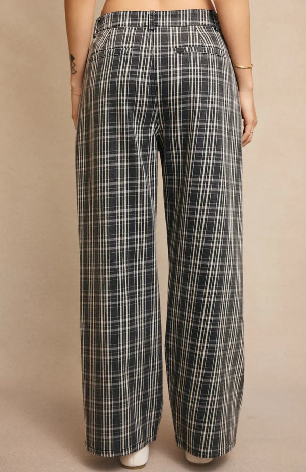 back view of the model wearing the sawyer pants. shows the faux pockets. also shows the wide leg, the plaid print, and the grey color. 