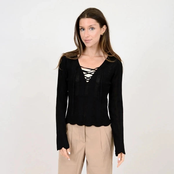 front view of the model wearing the medellin long sleeve v neck pullover. shows the v neck with criss cross detailing.  also shows the scallop detailing on the bottom hem and cuffs, and the fitted look 