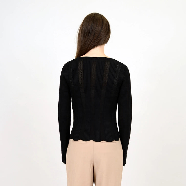 back view of the model wearing the medellin long sleeve v neck pullover. shows the scalloped bottom hem. also shows the fitted style and the sheer lines throughout. 