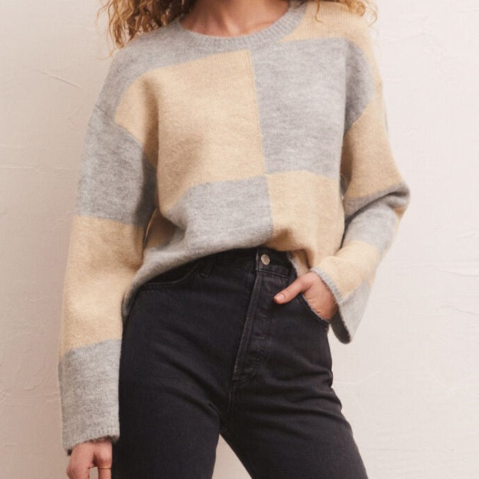 front view of model in sweater. shows crew neckline, wide sleeves, checkered print, and relaxed fit.