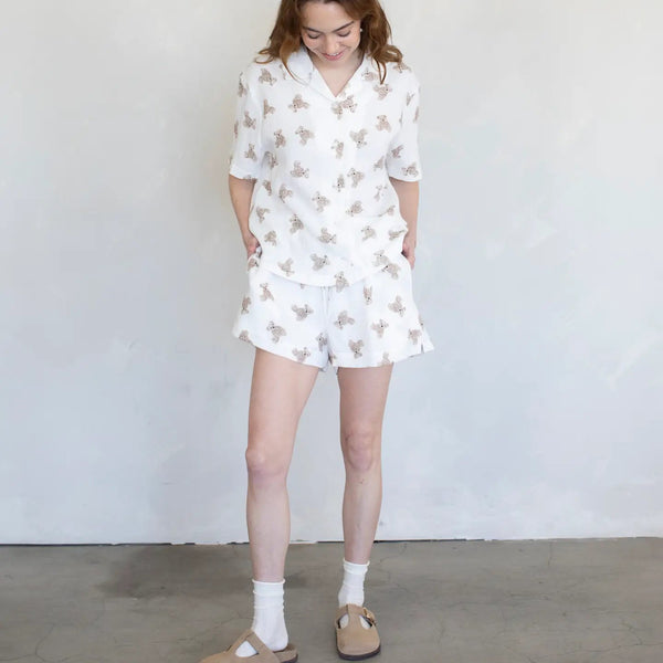 Woman wearing a white shorts with a teddy bear pattern, standing against a plain background
