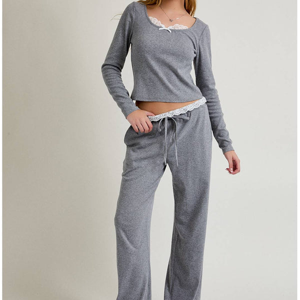 Woman wearing a gray long-sleeve top and pants on a plain background