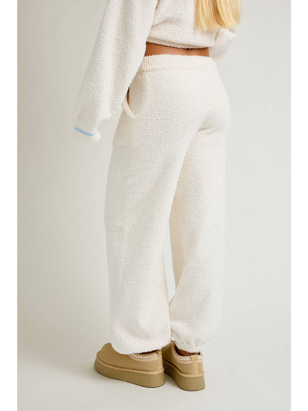 Person wearing white textured pants and beige shoes on a plain background