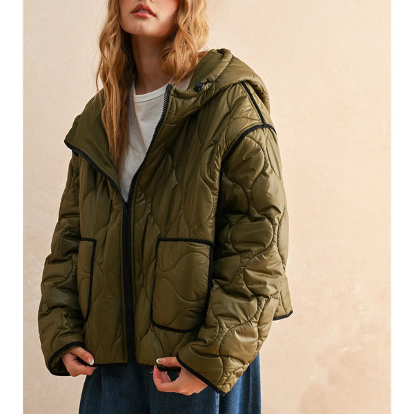 Woman wearing a green puffer jacket against a beige background