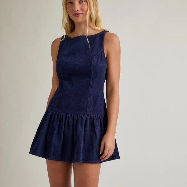 model wearing navy dress that is sleeveless on a cream background.