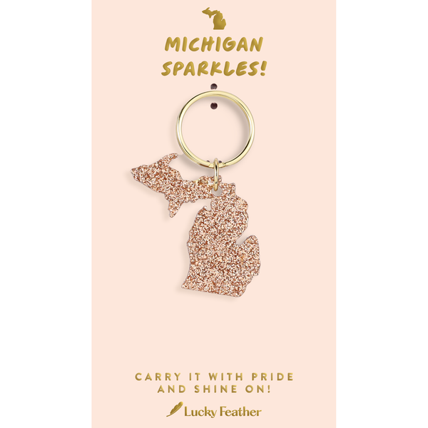 Keychain shaped like the state of Michigan on a pink card with text, featuring the brand 'Lucky Feather'.