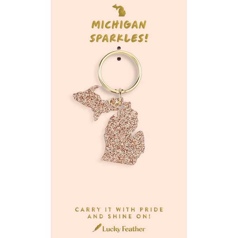 Keychain shaped like the state of Michigan on a pink card with text, featuring the brand 'Lucky Feather'.
