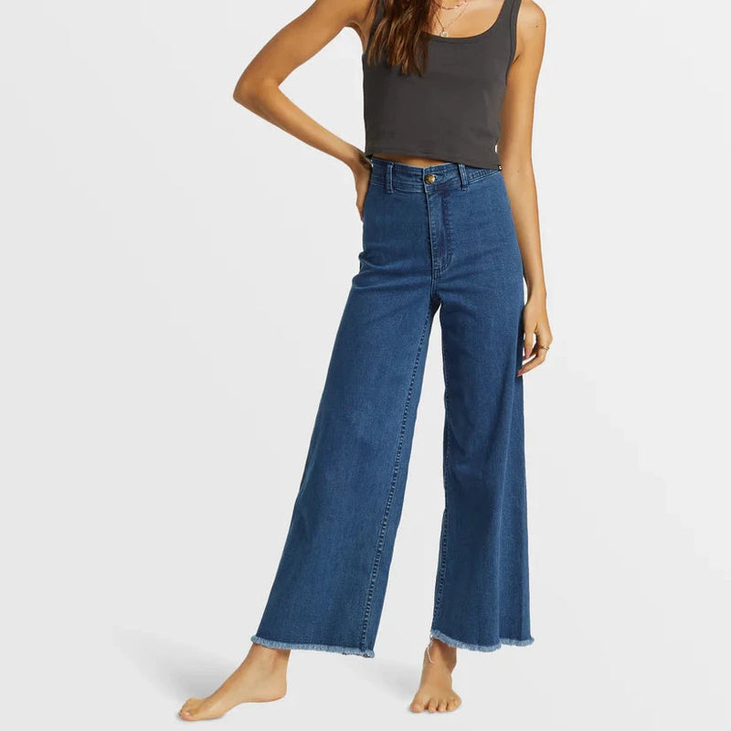 front view of the model wearing the free fall indigo wide leg jeans. shows the button closure. also shows the bottom raw hem, the high rise and the wide leg. 