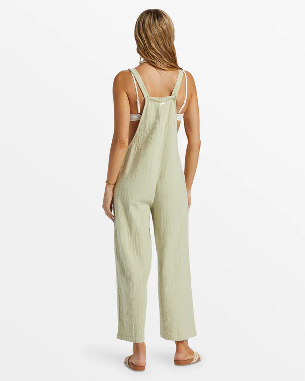 back view of the model wearing the pacific time jumpsuit. shows the adjustable button straps. also shows the relaxed fit and the straight legs. 
