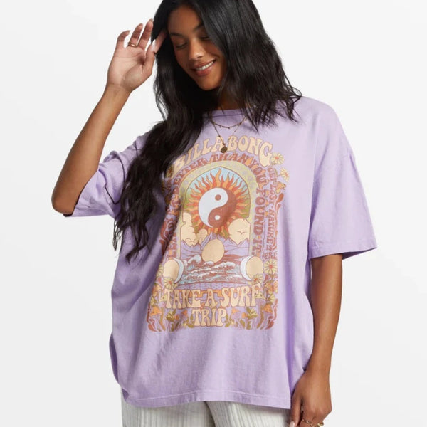 front view of the model wearing the surf trip oversized t shirt. shows the dropped shoulders. also shows the front graphic, the loose crew-neckline and the oversized fit. 