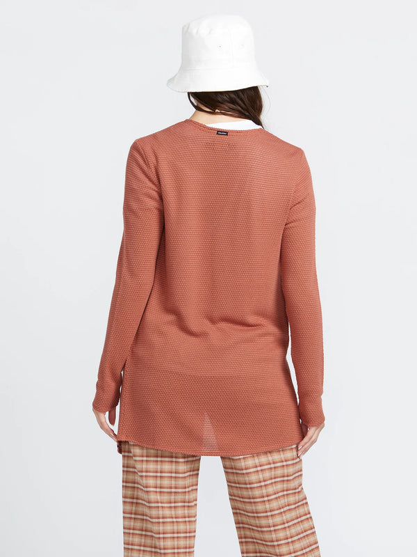 back view of the model wearing the go go wrap cardigan. shows the volcom tag and the neck. also shows the textured detailing throughout and that it is a longer cardigan. 
