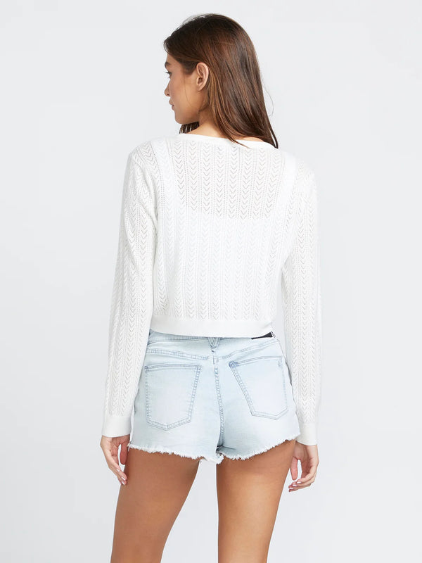 back view of the model wearing the shello there cardigan. shows the pointelle knit. also shows the cropped length, the back is little longer than the front, and the long sleeves. 