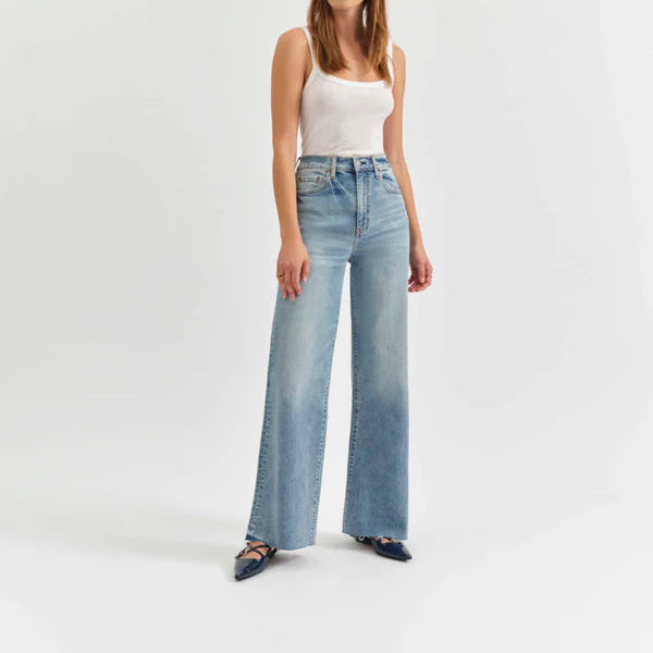 Woman wearing a white tank top and light blue jeans on a white background
