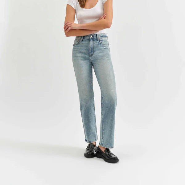 front view of the model wearing light blue jeans and a white top on a white background, shows the straight legs and the high rise of the jeans.