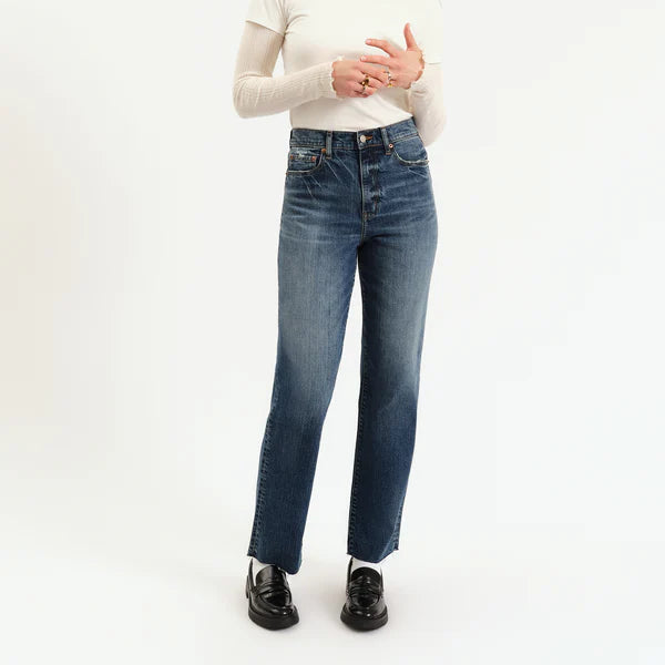 Woman wearing a white long-sleeve shirt and blue jeans on a white background