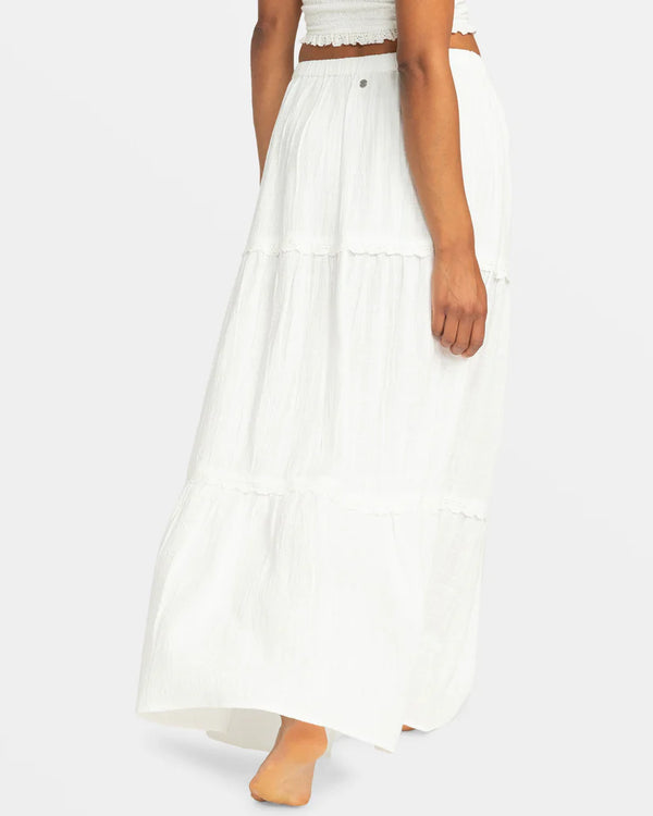 back view of the model wearing the beachside tiered maxi skirt. shows the mid rise. also shows the elastic waistband, the pull on closure, and the multiple tiers.