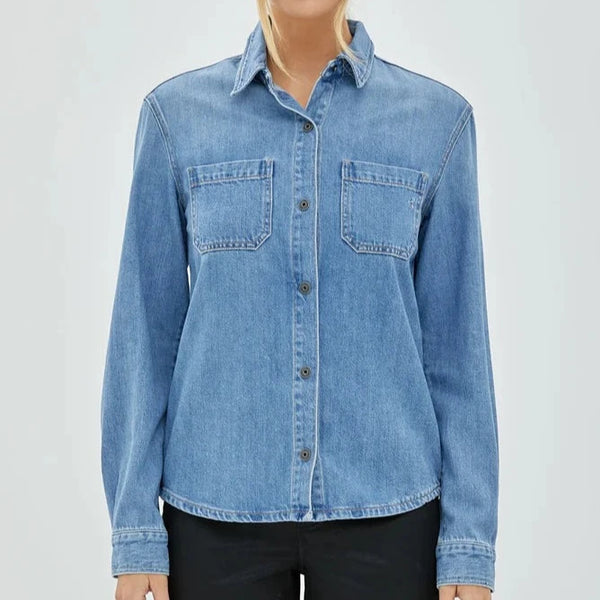 front view of the model wearing the abbey denim shirt. shows the collared neckline. also shows the front button closure, the round bottom hem, and the two front patch pockets. 