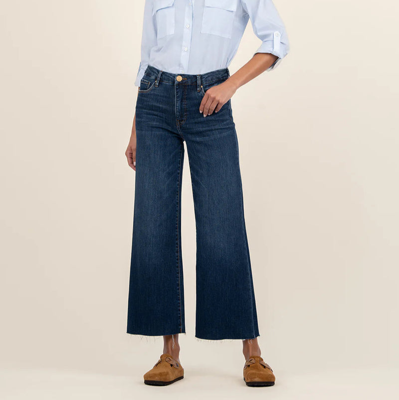 Person wearing a light blue shirt and dark blue jeans on a beige background