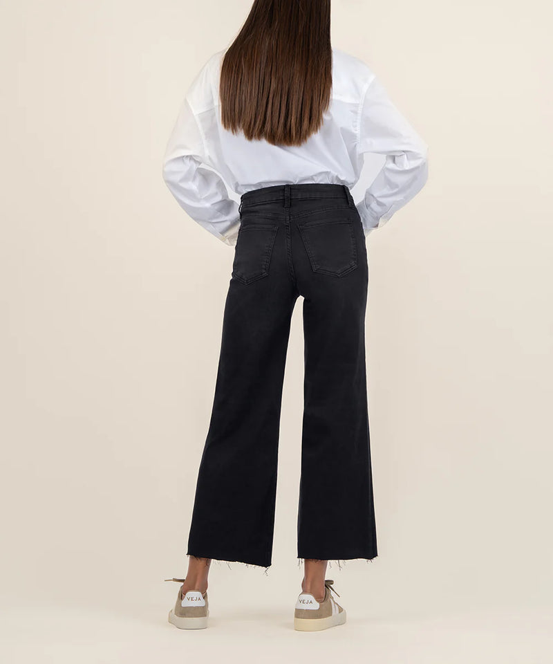 Person wearing a white blouse and black pants on a beige background