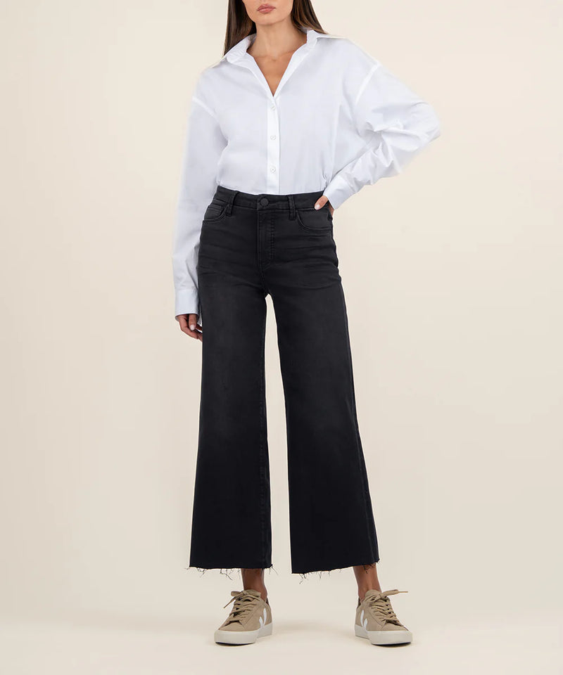 Person wearing a white shirt and black wide-leg pants on a beige background