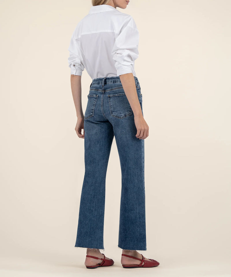back view of the model wearing the meg high rise wide leg jeans. shows the back patch pockets. also shows the raw hem, the acid wash color, and the wide legs. 