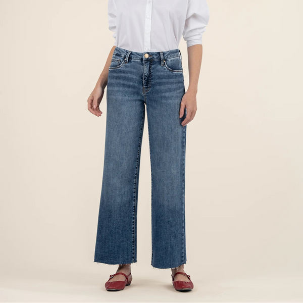 front view of the model wearing the meg high rise wide leg jeans. shows the raw hem. shows the front pockets, the acid wash color, the button/zipper closure. 