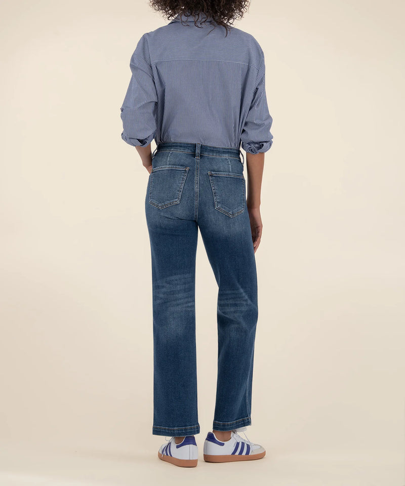 Person wearing a blue denim shirt and jeans on a beige background