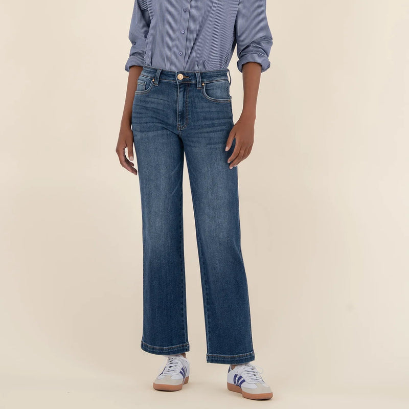 Person wearing a blue shirt and jeans on a beige background