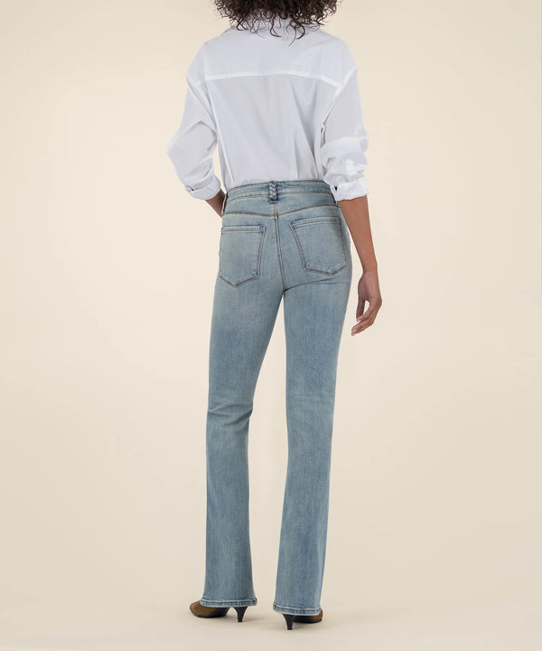 Person wearing light blue jeans and a white shirt on a beige background