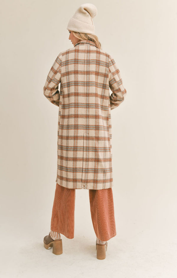 Back view of model wearing the plaid jacket. Shows the knee length of the coat. Also shows the faux slit on the bottom middle of the coat. 